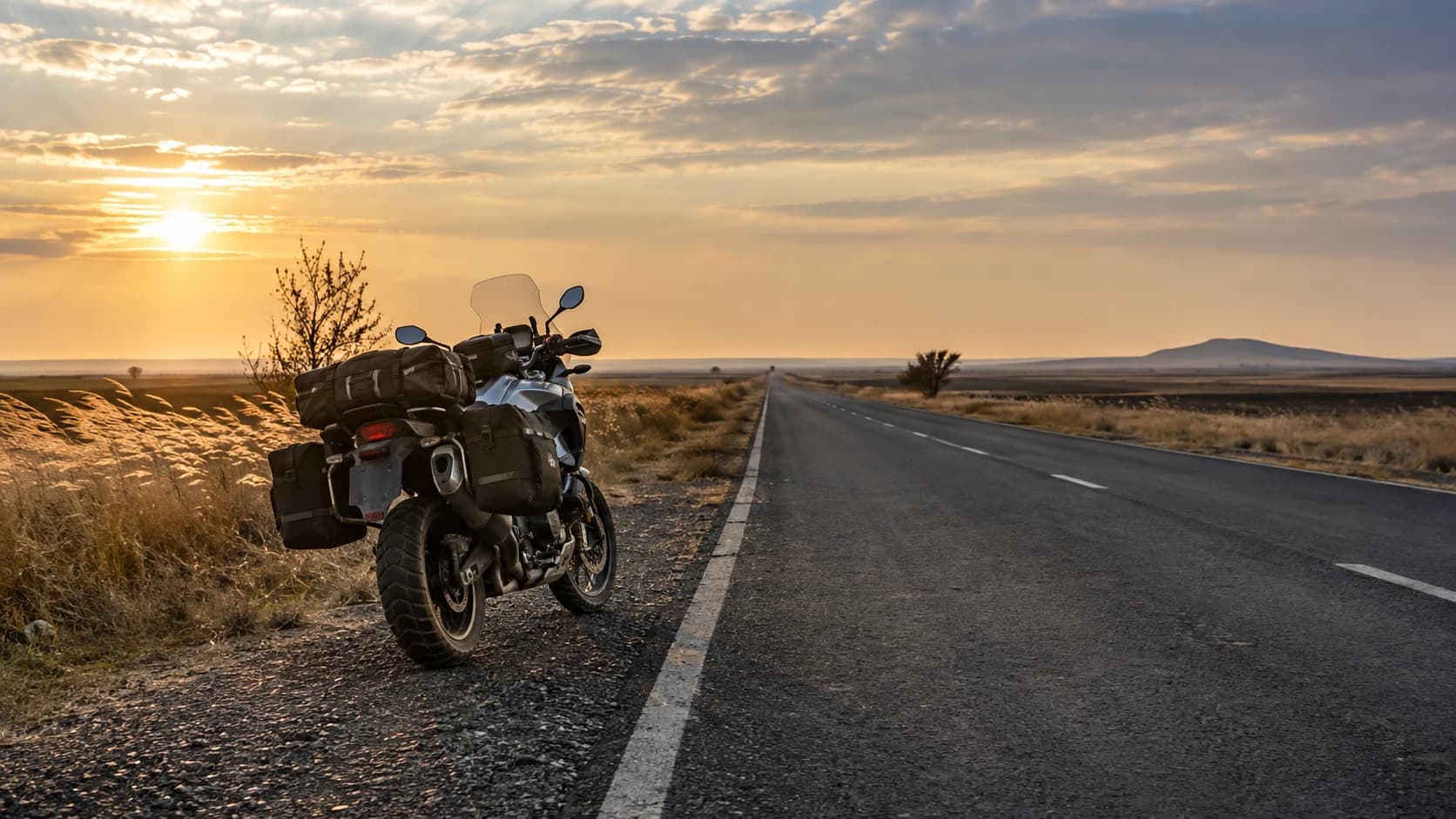 motocicletă touring pe drum drept de câmpie în lumina joasă de toamnă