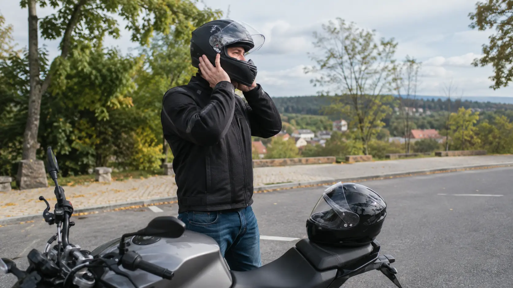 Motociclist echipat punând o cască integrală înainte de plecare
