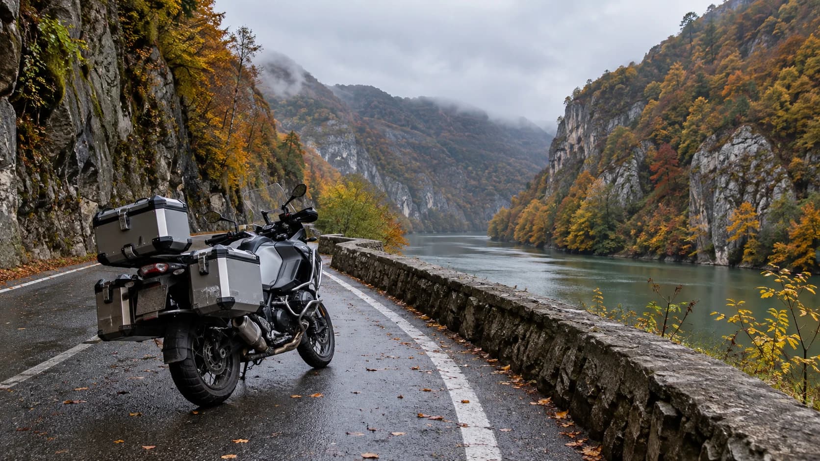 Motocicletă touring pe un drum de defileu cu versanți împăduriți toamna