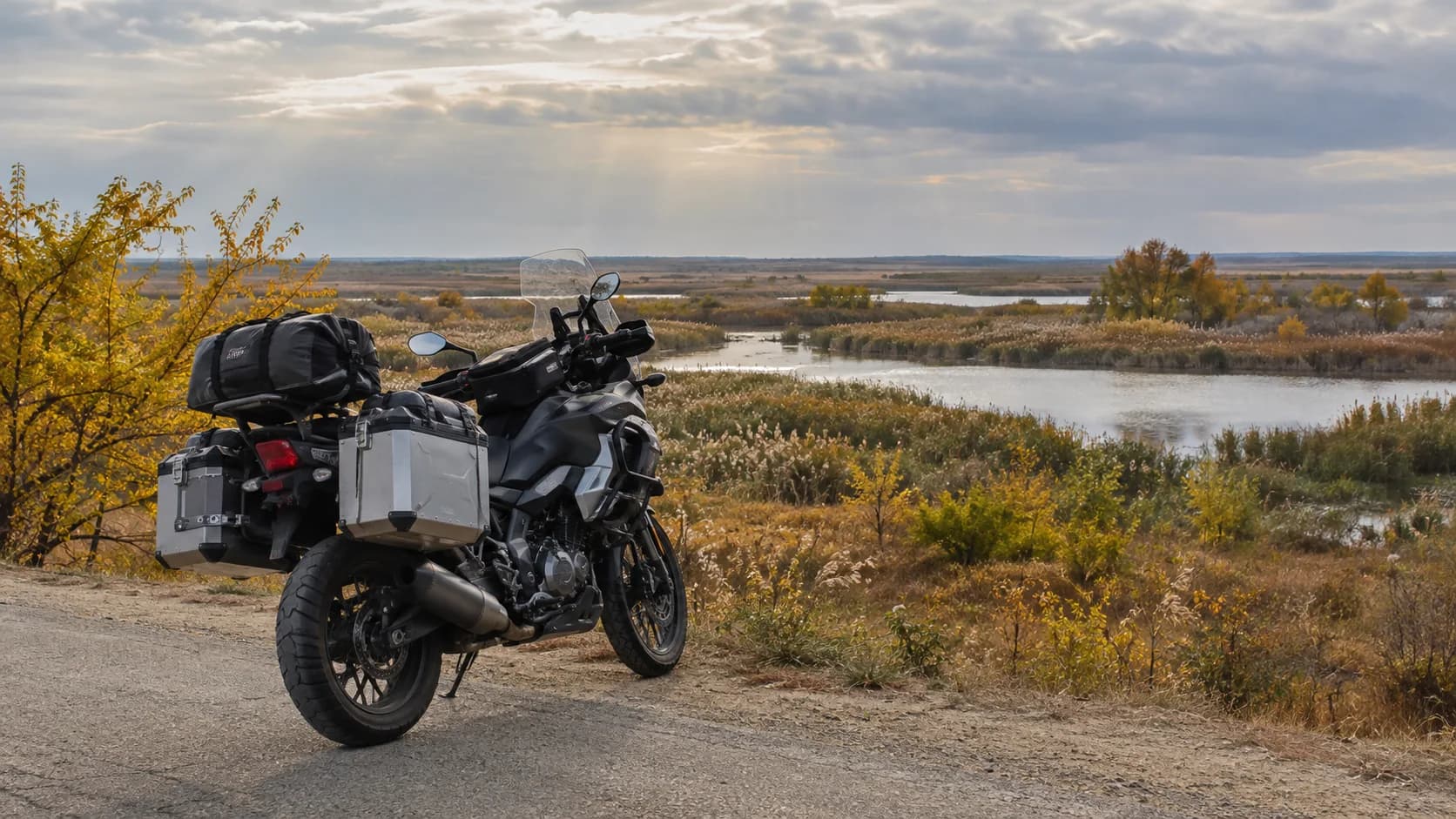 Motocicletă de touring parcată lângă stufăriș și apă în Dobrogea toamna