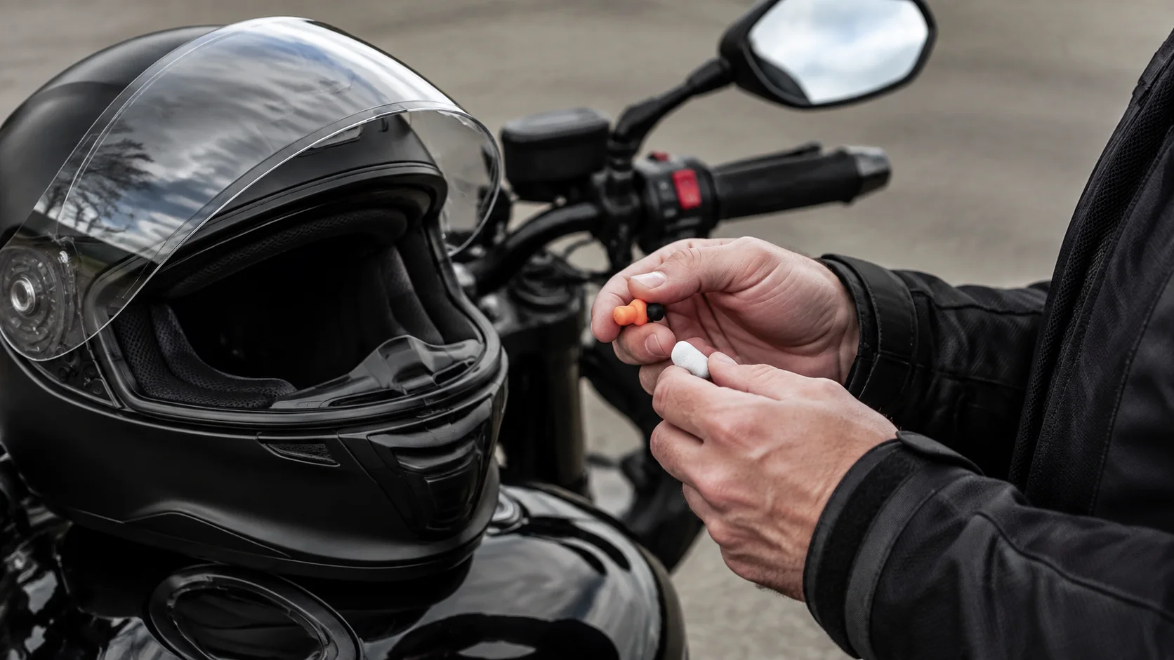 Motociclist pregătind dopuri de urechi lângă o cască integrală pe rezervor