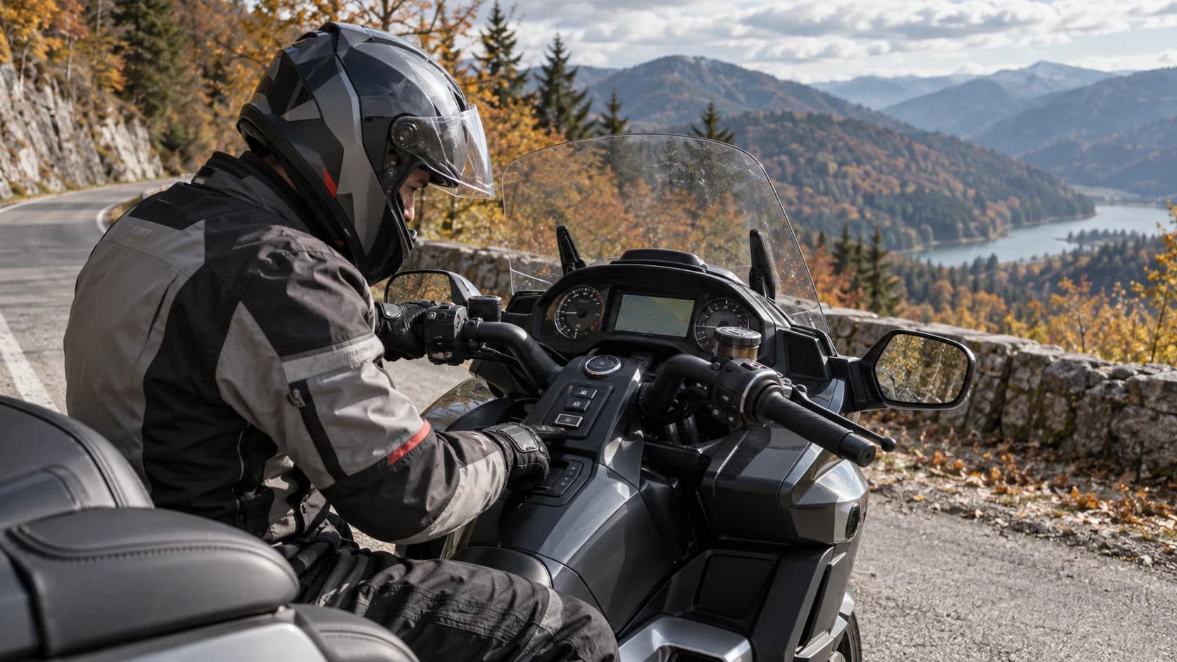 Rider în echipament touring verificând comenzile unei motociclete pe marginea unui drum de munte