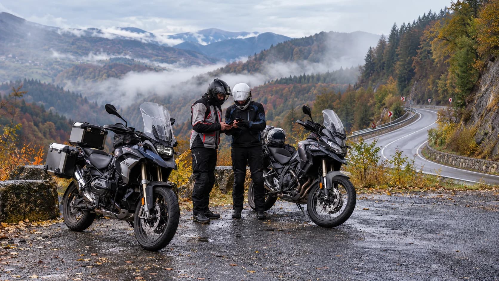 Două motociclete touring oprite la un punct de belvedere pe un drum montan de toamnă