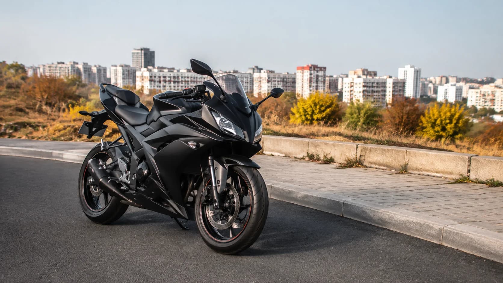 Motocicletă sport de cilindree mică pe un drum curat la marginea orașului