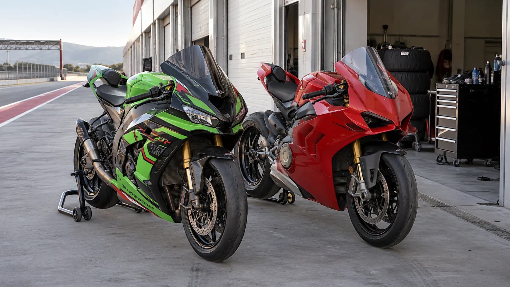două motociclete sport de circuit fotografiate în paddock fără sigle vizibile